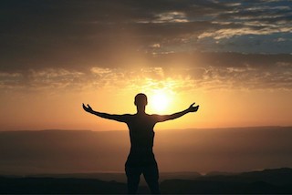 personne ouvrant les bras devant l'océan au coucher du soleil: connexion à soi